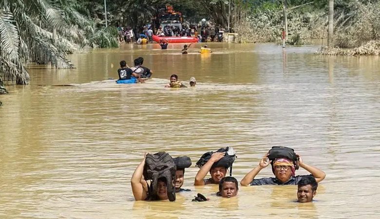 Warga mengarungi banjir setinggi leher orang dewasa di Kuala Simpang, Aceh Tamiang, Aceh, 30 November 2025.