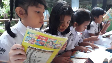 Ilustrasi siswa SD membaca buku pendidikan.