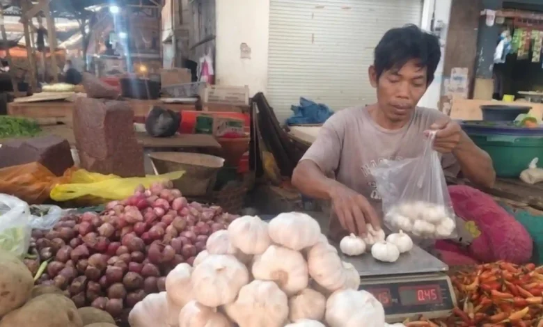 Nurmansyah, pedagang bawang di Pasar Kebon Roek, Ampenan, Kota Mataram, menimbang bawang putih dagangannya.