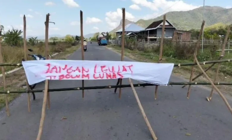 Pagar bambu dan spanduk protes membentang menutupi ruas Jalan Baru Lamusung-Senayan, Kabupaten Sumbawa Barat, Rabu, 22 Juli 2026.