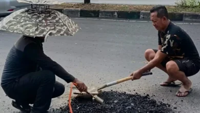 Warga menambal lubang di Jalan Gajah Mada, depan Kampus UIN Mataram dengan material seadanya.