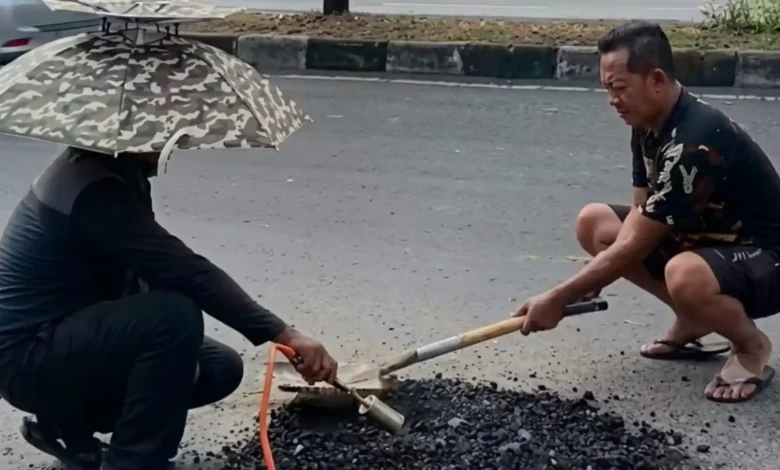 Warga menambal lubang di Jalan Gajah Mada, depan Kampus UIN Mataram dengan material seadanya.