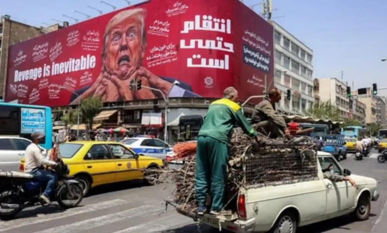 Para pengendara mobil melintas di depan papan reklame besar yang menjanjikan pembalasan terhadap Presiden AS Donald Trump di sepanjang Jalan Jomhouri di pusat Teheran, Iran.