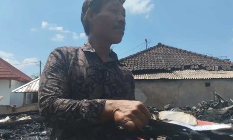 Warga Desa Sade, Marwan (55), mencari sisa-sisa naskah lontar kuno yang terbakar bersama rumahnya, Minggu, 23 Agustus 2026.
