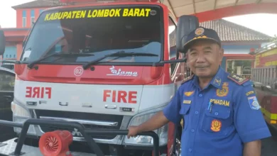 Kepala Dinas Pemadam Kebakaran dan Penyelamatan Lobar, Suherman, berdiri di samping salah satu armada mobil operasional damkar di mabes Damkarmat, Gerung, September 2026.