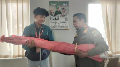 Kepala Bidang Ketertiban Umum Satpol PP Lobar, Abdurrahman (kanan), saat menyerahkan kembali payung milik pedagang yang sebelumnya disita, Senin, 21 September 2026.